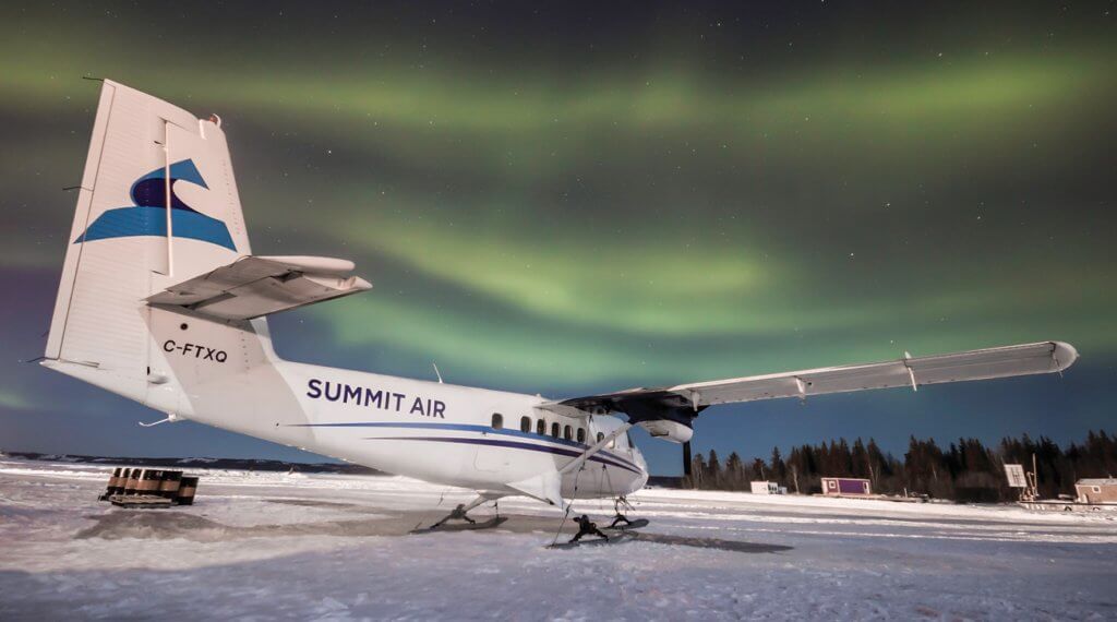 A ski-equipped Summit Air Twin Otter basks in the glow of the northern lights. Daniel Acton Photo