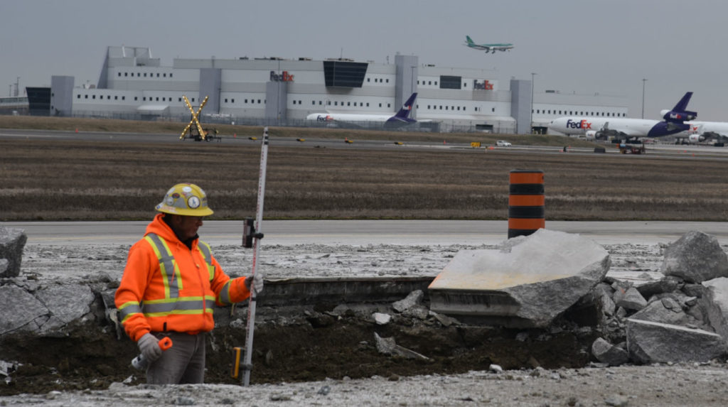 A worker stands in a crater created during work on Taxiway Hotel, the primary arterial taxiway connecting to the west end of Runway 05/23 at Toronto Pearson International Airport. GTAA Photos
