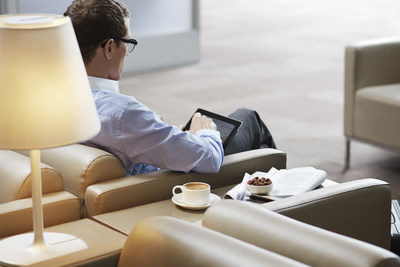 Man sits in chair with tablet computer in passenger lounge