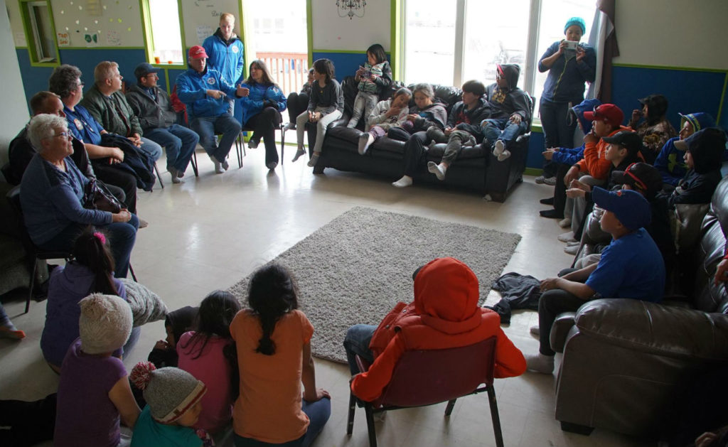 Group of people sitting in a circle, including adults and children..