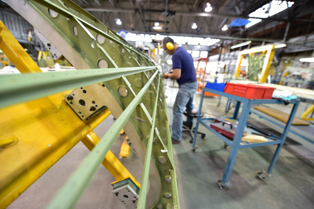 Man works on aircraft fuselage at manufacturing facility.