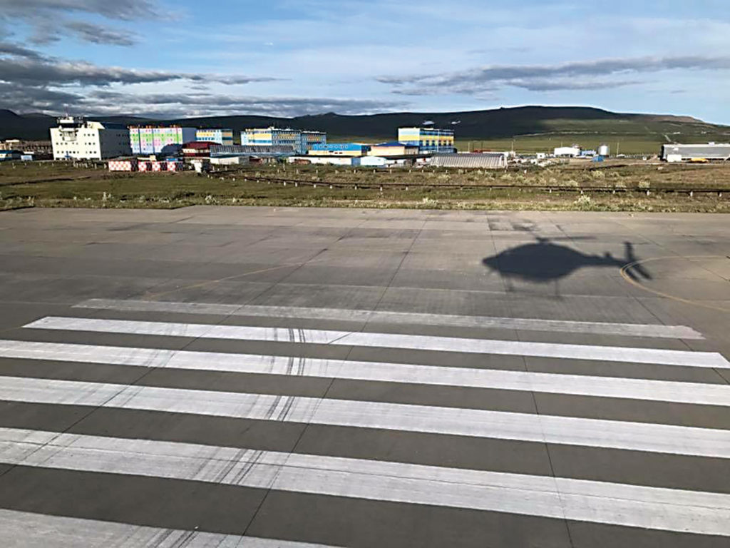 Helicopter casts its shadow on tarmac below.