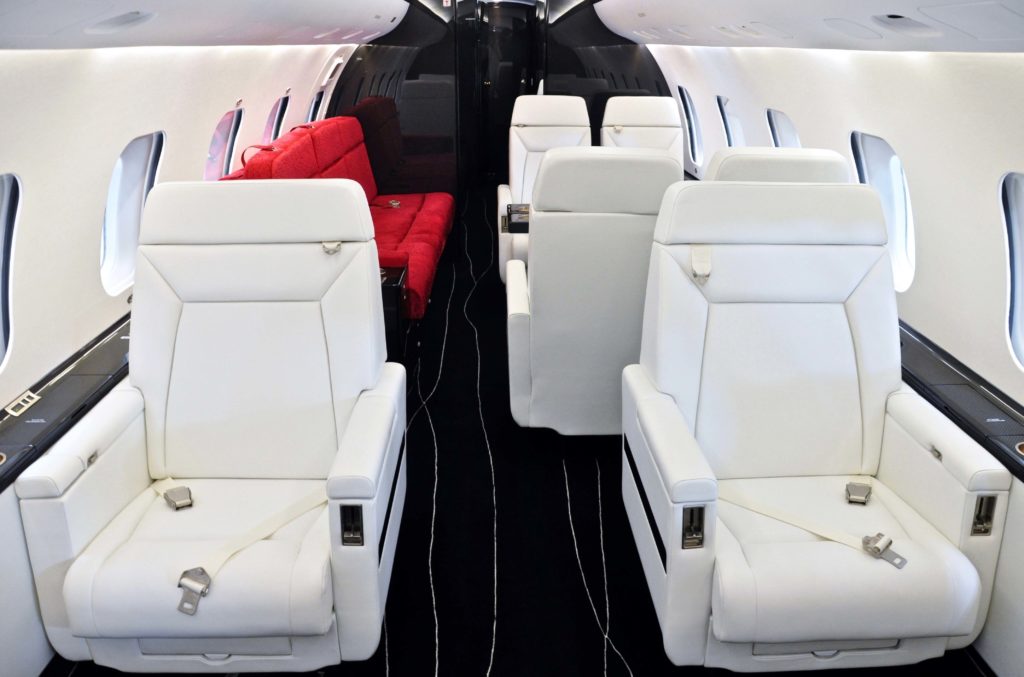 New white leather seats towards the front of the photo. The cherry-red divan, which provides a splash of colour in the mid-cabin, is complemented by a second black three-seat divan in the aft section. 