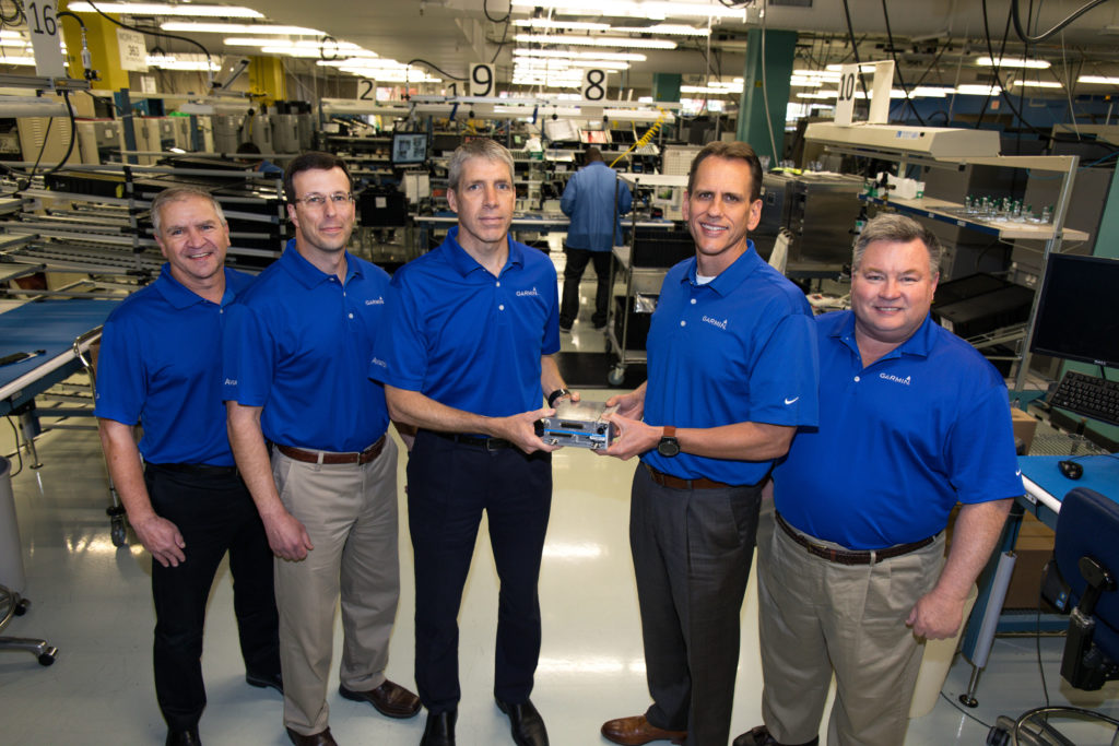 Five men stand in a horizontal row, with the middle two holding the GTX 3000 transponder.