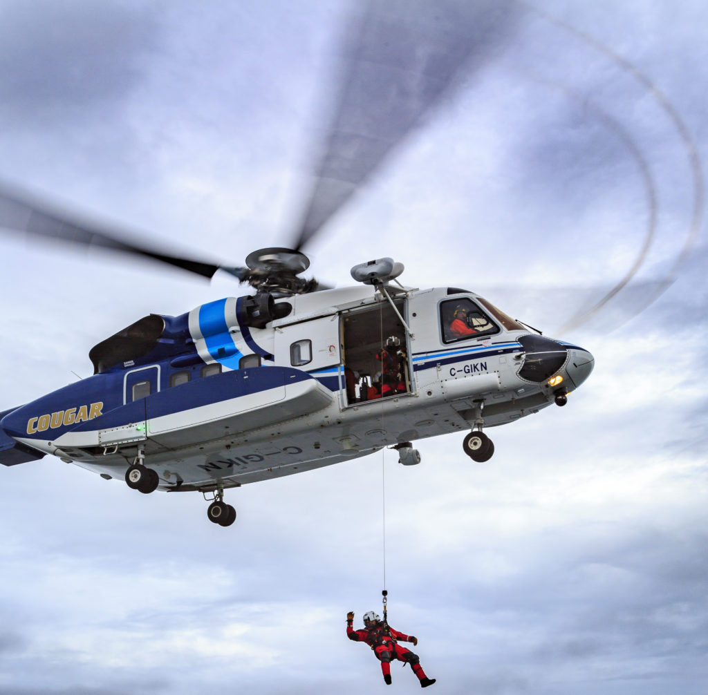 Cougar Sikorsky S-92 helicopter with rescue working hanging below it on longline
