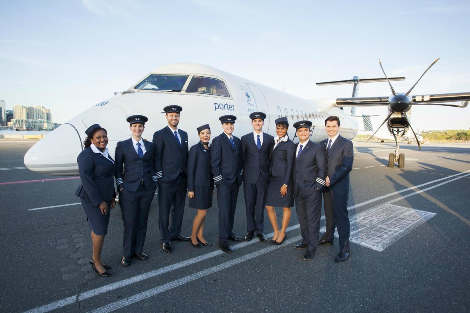 Porter Airlines staff stand in front of one of the company's 29 Bombardier Q400 aircraft. 