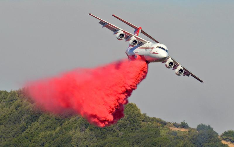 Plane dumps flame retardant on a fire