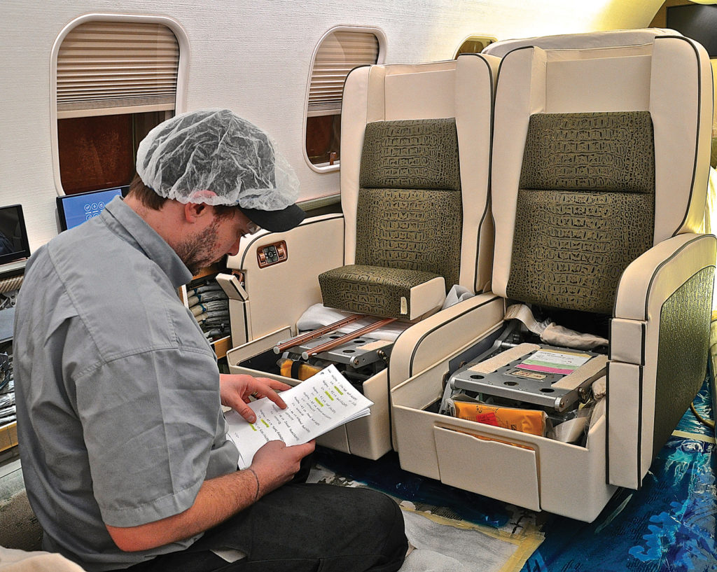 Technician sits inside aircraft.