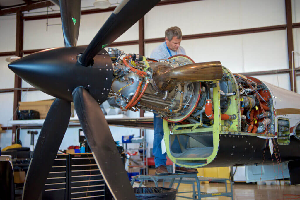 Man works on exposed aircraft engine.