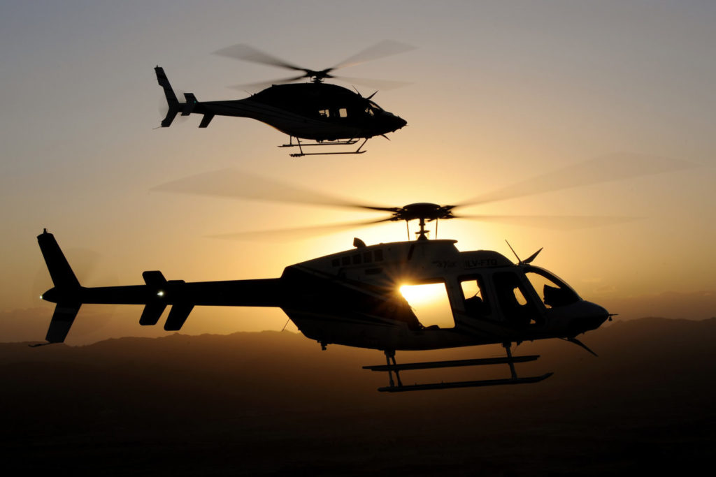 Two helicopters silhouetted against setting sun