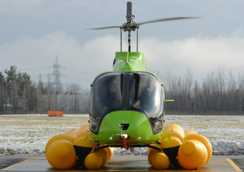 Bell 505 with emergency flotation system rests on helipad.
