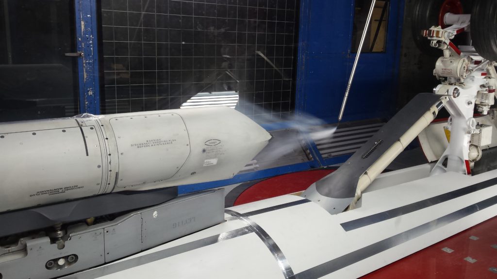 Wind whips over the inverted CF-188 nose landing gear and sniper pod in a National Research Council of Canada wind tunnel.