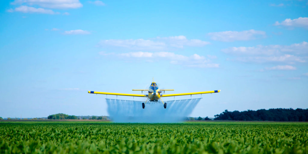 Air Tractor aircraft flies over field, spraying crop