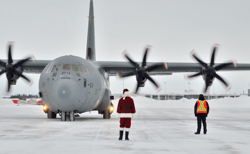 Santa Claus and a member of the groundcrew wait to greet the aircrew on board a CC-130J Hercules aircraft from 8 Wing Trenton, Ont., as it lands at 5 Wing Goose Bay, N.L., on Dec. 10, 2018. MCpl Krista Blizzard