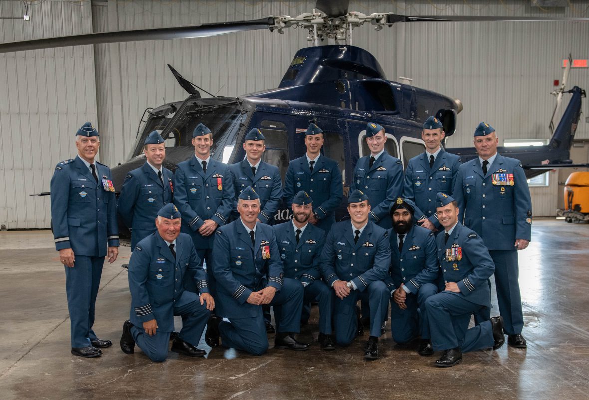 Graduates of the rotary wing course, along with school personnel, BGen Mario Leblanc (standing, left) and HCol Andy Fletcher (kneeling, left), gather for a photo after receiving their pilot wings. RCAF Photo