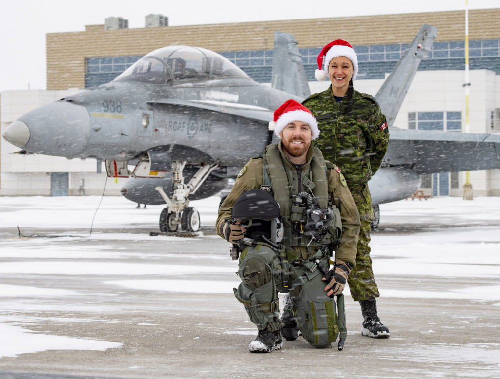 CF-188 Hornet pilot Capt Felix St-Jean (kneeling), supported by maintainer Cpl Amélie Tremblay-Gauthier, will escort Santa through Canadian airspace in eastern Canada on Dec. 24, 2019. Both are from 3 Wing Bagotville, Que. Cpl Louis Gagné Photo