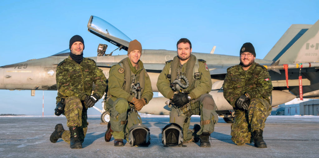 Avr Jesse Tratch, Maj Kyle Wilson, Capt Brett Bobowski and Cpl Vincent Cloutier, all of 401 Squadron, Cold Lake, Alta., pose for a photo in front of a CF-188 Hornet. Maj Wilson and Capt Bobowski, with the help of their ground crew, Avr Tratch and Cpl Cloutier, will be piloting the CF-188 scheduled to escort Santa into Canadian Airspace on Dec. 24, 2019 as part of the NORAD Tracks Santa Initiative. Cpl Maxime St-Cyr Photo