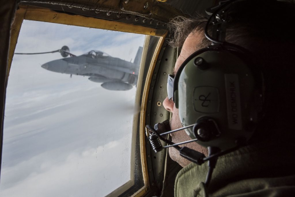 WO Ron Demchuk, a load master with 435 Transport and Rescue Squadron based out of Winnipeg, watches for any issues as a CF-188 Hornet utilizes a CC-130 Hercules refueling aircraft to top up while conducting an exercise during Operation Nanook in 2017. Cpl Anthony Laviolette/RCAF Photo